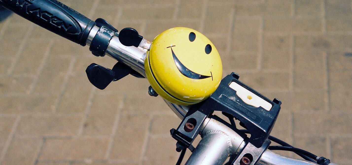 Smiley-Fahrradklingel an einem Fahrradlenker.